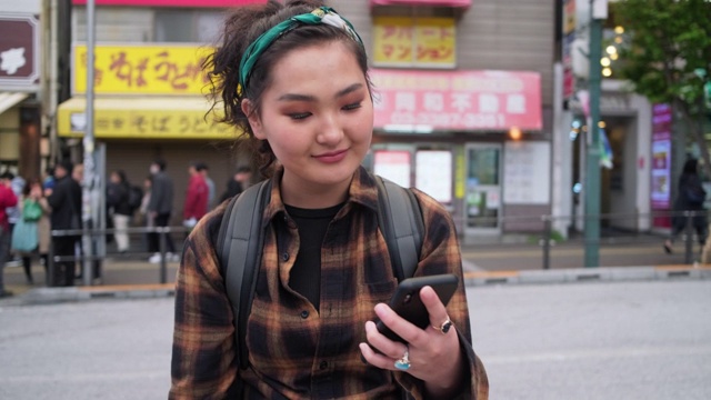 在东京，年轻的蒙古女背包客在用智能手机视频素材