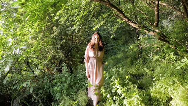 黑发女人走过森林，欣赏树木。美丽的女孩在户外享受大自然。视频素材