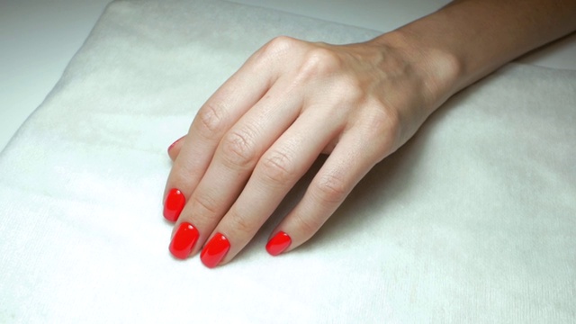 在美容院，一个女孩手上漂亮的红色指甲。慢动作视频下载