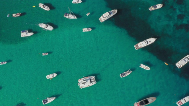 从上面俯瞰，鸟瞰满是船只和豪华游艇的美丽海湾。绿松石般的海水沐浴着绿色和多岩石的海岸。丽莎·鲁贾，翡翠海岸(翡翠海岸)撒丁岛，意大利视频下载