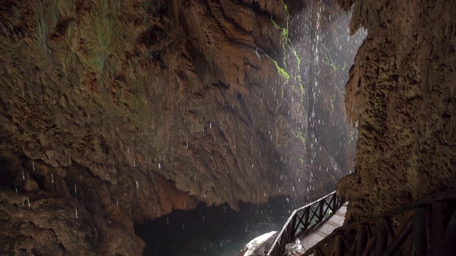 在一个小洞里，水滴滴进水里。瀑布在热带雨林景观。视频下载