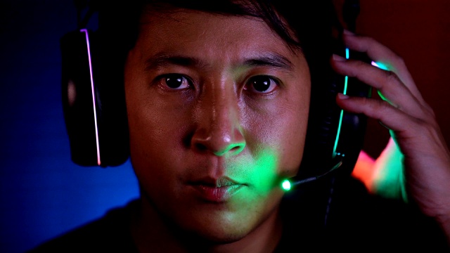 近距离前视图严肃的亚洲电子竞技玩家玩视频游戏与他的耳机看摄像头视频下载