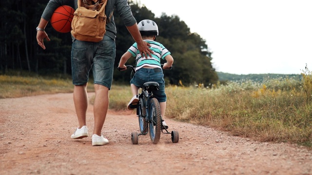 父亲正在公园里教他的小儿子骑自行车视频素材