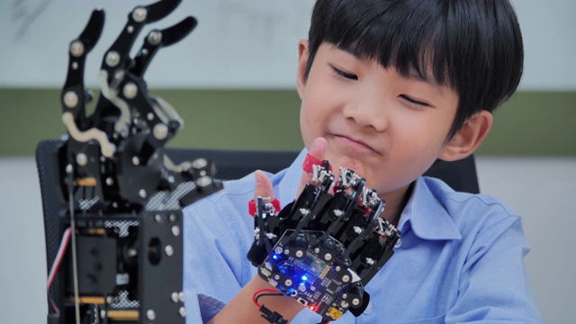 男孩在电脑上构建和编程，并建造一个机器人手臂作为学校的科学项目。他对自己的工作非常满意。教育、技术、团队、科学、人本理念。教育的主题视频素材