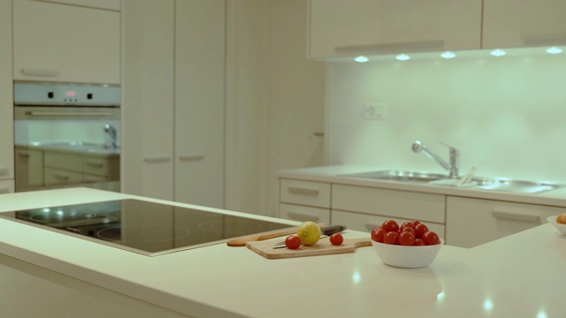 现代风格的厨房设计，扁平的白色橱柜，白色的石英台面，电动炉灶，炉灶和水槽。视频素材