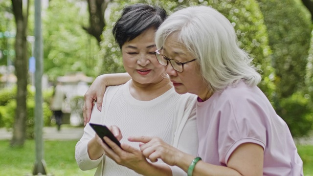 两名台湾资深女性在公园看智能手机的慢动作视频视频素材