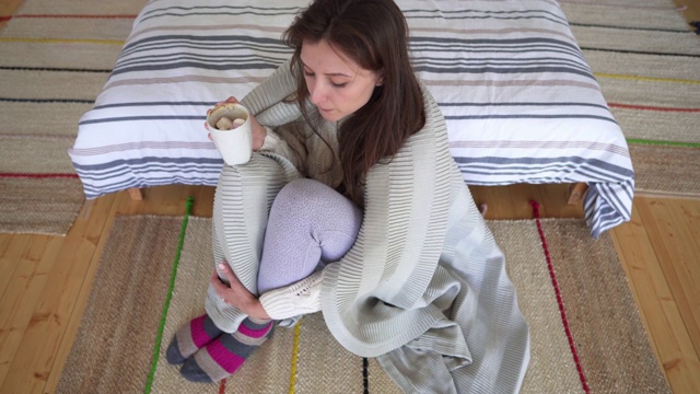 快乐的女孩坐在家里的地板上，躲在毯子后面。斯堪的纳维亚室内设计使用天然材料。Lagom概念。视频下载