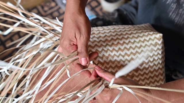 特写的妇女编织一个干叶编织篮子，篮子的手工工艺生产视频素材