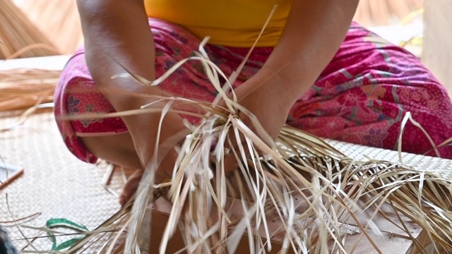 特写的妇女编织一个干叶编织篮子，篮子的手工工艺生产视频素材