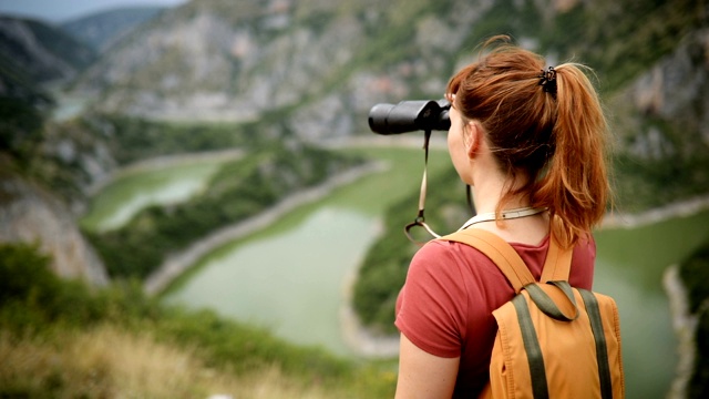 年轻的徒步女郎到达山顶，欣赏风景视频下载