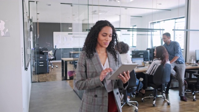 积极的商业女性在办公室里行走并使用数字平板电脑视频素材
