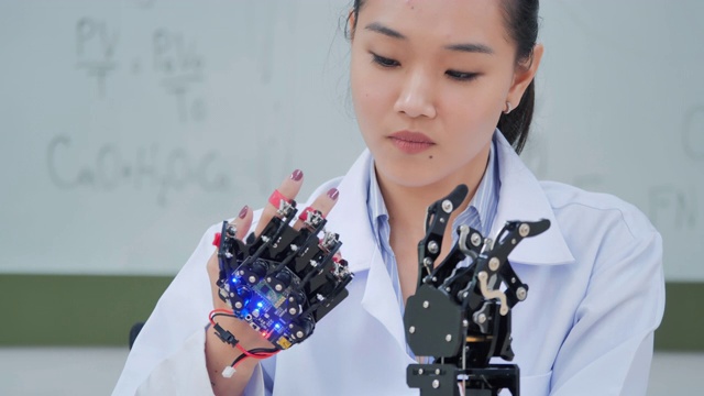 一个未来主义的假肢机器人手臂由一个十几岁的女孩开发工程师在一天的研究实验室工作到很晚。手臂移动手指。教育、技术、团队合作、后期工作、创新、科学、人本理念。教育的主题。4.0行业视频下载