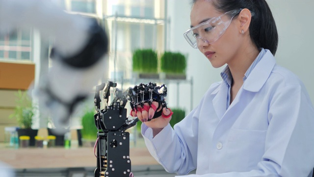 一个未来主义的假肢机器人手臂由一个十几岁的女孩开发工程师在一天的研究实验室工作到很晚。手臂移动手指。教育、技术、团队合作、后期工作、创新、科学、人本理念。教育的主题。4.0行业视频素材