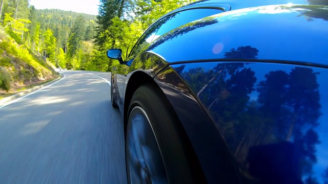 在一个阳光明媚的日子里，一辆优雅豪华的跑车行驶在蜿蜒的山路上视频素材