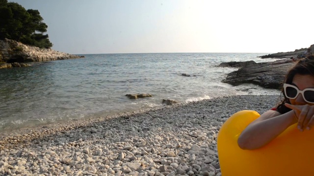 女人日光浴在黄色的空气沙发海阳光沙滩夏天的时间视频下载