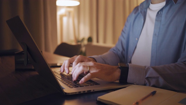 一个男人用手在桌上的笔记本电脑上输入数据的细节视频素材