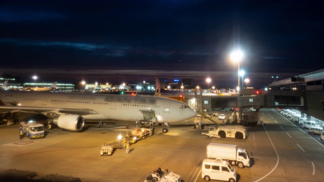 延时:黄昏时分，在机场，货运汽车将货物和行李装载到飞机上。缩小照片视频素材