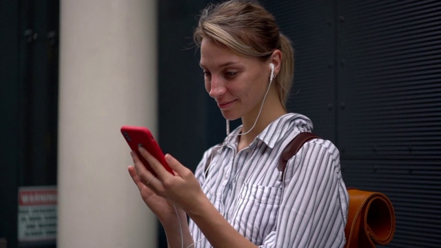 快乐女人通过手机上的应用程序听音乐，同时阅读网页上的内容文本的慢动作效果视频素材