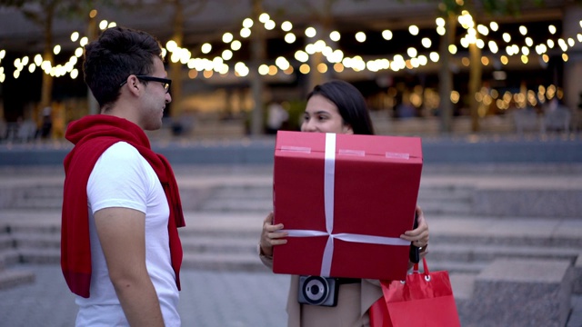 西班牙潮人给礼物盒与礼物积极惊喜的女朋友等在城市设置视频下载