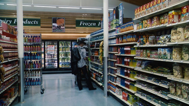 中等角度的男人在杂货店或超市过道购物。食物在书架上。视频素材