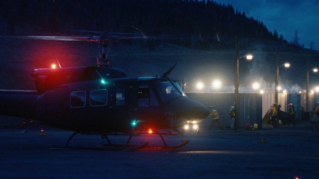 中等角度的直升机，有闪光灯准备起飞或起飞。直升机起飞。在bg的金属集装箱旁，工人们戴着安全帽四处乱窜。视频下载