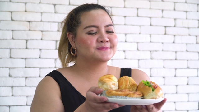 正面图:泰国胖女人闻到最喜欢的甜面包很开心视频素材