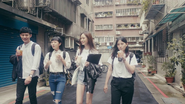 一群年轻的亚洲学生走在街上喝着珍珠奶茶(慢镜头)视频下载