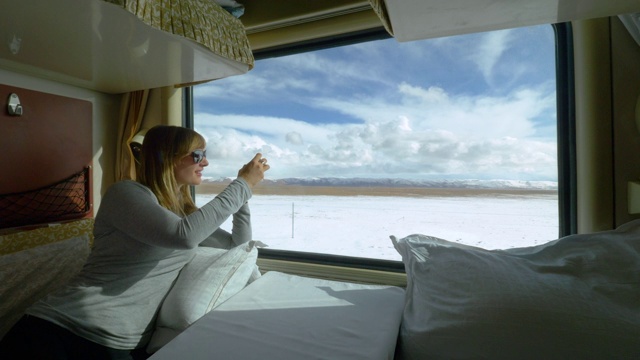 近距离观察:一名女子在火车上拍摄西藏雪景。视频下载