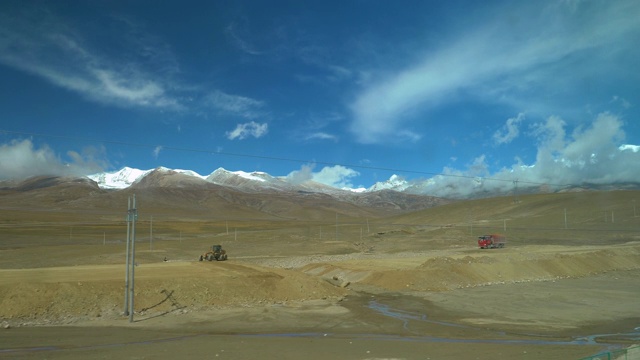 在令人惊叹的西藏，雪山耸立在正在建设的公路上。视频下载