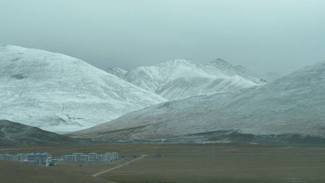 慢镜头:白雪覆盖的山脉俯瞰喜马拉雅山脉的平原和偏远城镇。视频素材