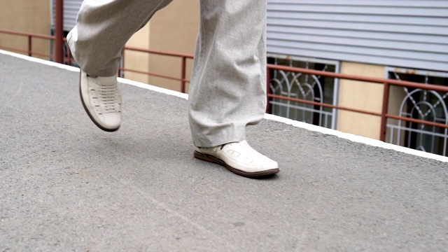 男人慢慢自信地走在小镇的小路上，穿着白色的鞋子视频素材