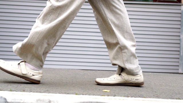 照片中男人穿着鞋走在瓷砖路上。城市环境视频素材