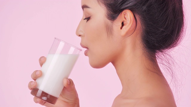 年轻快乐的女人喝鲜奶在粉红色的背景。清洁平衡的健康食品理念。健康饮食与健身理念。有机食品。医疗保健理念。视频:多样化的肖像视频下载