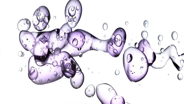 近距离和缓慢的动作，清澈的紫色液体从右边倒入水中，变成漂浮在白色背景上的大气泡视频素材
