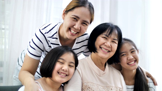 慢动作的幸福亚洲家庭在家里一起微笑，多代女性视频下载