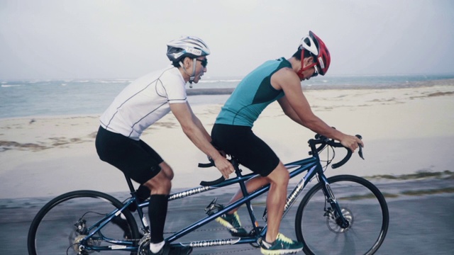 一个盲人铁人三项运动员和他的向导在他们的双人自行车训练的中景视频素材