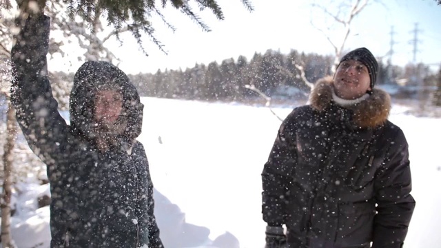 一个年轻的女人在男人旁边用雪摇着松枝视频素材