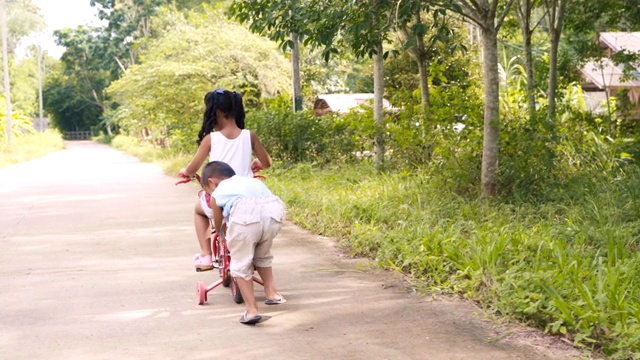 快乐的男孩和女孩在路上玩和骑自行车，笑着，幸福。视频素材