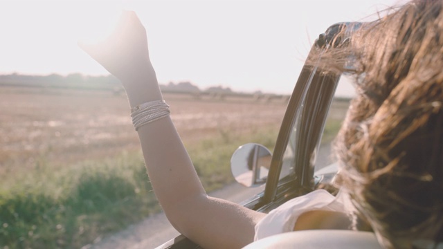 无忧无虑的年轻女子驾驶敞篷车沿着阳光明媚的乡村田野视频下载