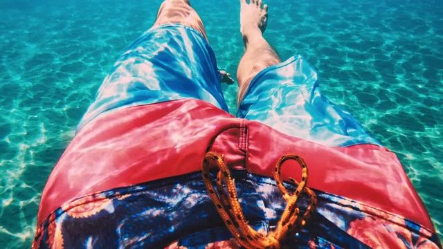穿着彩色泳衣的男人腿在水下游泳视频下载