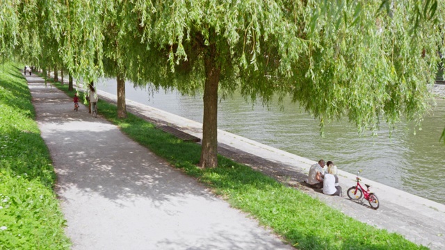丈夫和妻子在公园里骑双人自行车，他们的两个孩子在他们旁边视频素材
