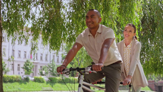 SLO MO夫妇在阳光公园骑双人自行车视频素材