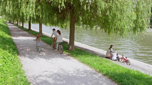 小女孩在公园里骑着她的自行车，旁边是她的父母在骑双人自行车视频下载
