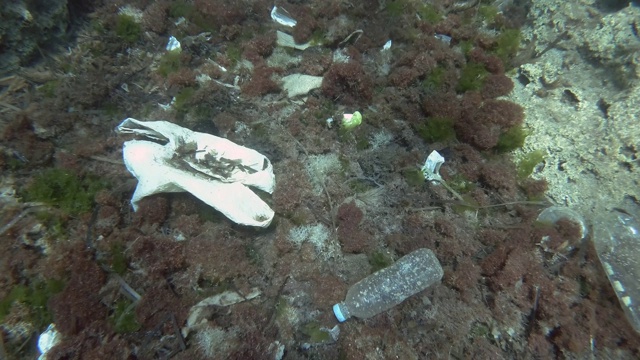 塑料污染，热带鱼游过覆盖着大量塑料垃圾的海底。缓慢的运动。欧洲地中海海床上的塑料瓶、塑料袋和盘子。视频素材