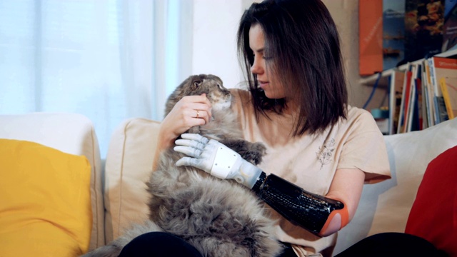 一个女孩用仿生手轻拍一只猫。视频下载