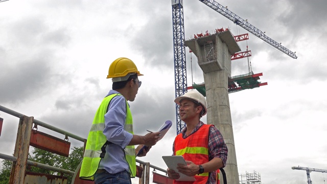 两名东南亚工程师在建筑工地谈论报告视频素材