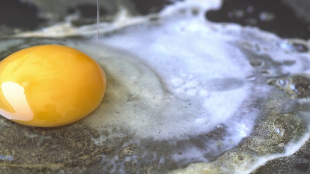 在平底锅里煎鸡蛋。打碎的鸡蛋掉进了煎锅里视频素材