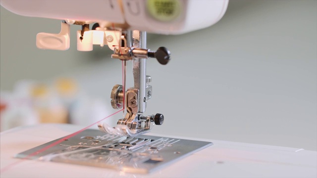 女裁缝的手在缝纫机上用直缝缝红衣服。视频下载