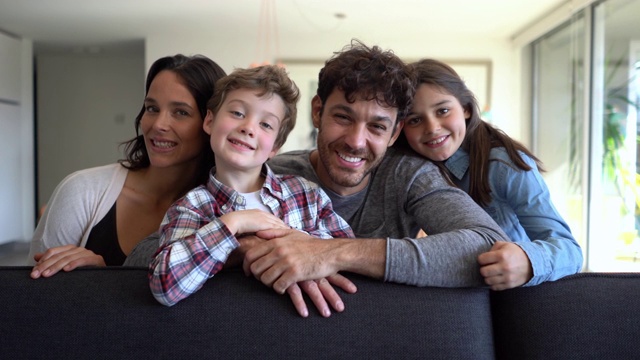 美丽的拉丁美洲家庭，两个孩子坐在沙发上对着镜头微笑，非常开心视频下载