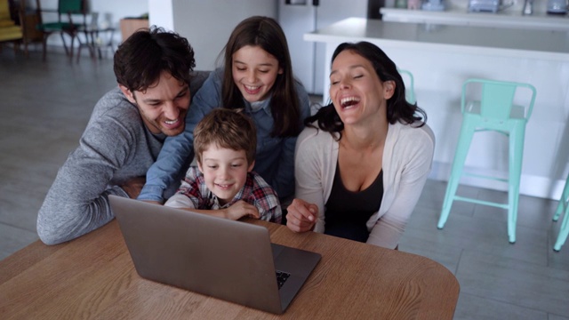 欢乐的四口之家正在家里的笔记本电脑上看一部有趣的电影视频素材